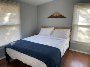 a large bed in a bedroom with two windows at Bright 3bdrm perfect location 2.5 mi to SPAC , Close to track, downtown and Saratoga hospital in Ballston Spa