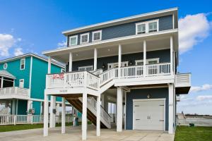 une grande maison avec une terrasse blanche et un garage dans l'établissement Seaside Sanctuary, à Galveston