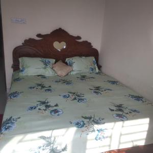 a bed with a wooden head board with blue flowers at Secured Family Studio Apartment-near Airport,AC,Fridge,WiFi,Stove in Dhaka