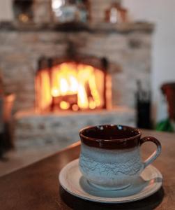 a coffee cup on a plate on a table with a fireplace at Lazaros Stonehouse in Pano Lefkara