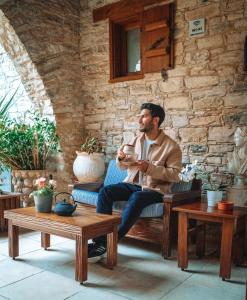 a man sitting on a couch in a room with tables at Lazaros Stonehouse in Pano Lefkara