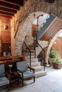 a lobby with a staircase with two chairs and a table at Lazaros Stonehouse in Pano Lefkara