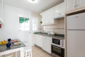 kuchnia z białymi szafkami i białą lodówką w obiekcie Villa Togio 2 by Villa Plus w Puerto del Carmen