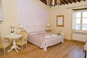 a bedroom with a pink bed and a table and chairs at B&B Anfiteatro in Lucca