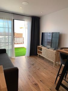 a living room with a couch and a television at Luxury Los Diamantes One Bedroom Apartment in Los Cristianos