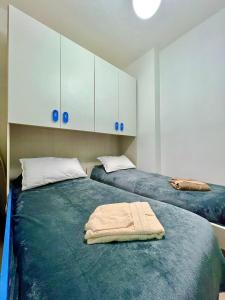 2 camas en una habitación con armarios blancos y toallas en Casa Riva Mare, en Riva Ligure