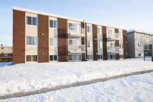a snow covered parking lot in front of a building at Modern & Stylish 1-Bedroom Unit in Edmonton