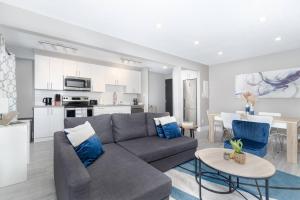 a living room with a gray couch and a kitchen at Modern & Stylish 1-Bedroom Unit in Edmonton