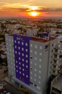 - une vue sur un bâtiment avec le coucher du soleil en arrière-plan dans l'établissement Sleep Inn Leon Antares, à León
