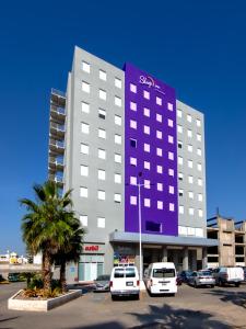 un gran edificio con coches estacionados en un estacionamiento en Sleep Inn Leon Antares, en León