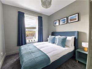 una camera con un letto blu e una finestra di Alt-na-craig a Rothbury