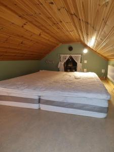 a large bed in a bedroom with a wooden ceiling at Lillastugan Sätuna in Falköping