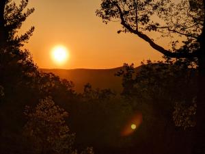 einen Sonnenuntergang in den Bergen mit Bäumen im Vordergrund in der Unterkunft Barefoot Hills in Dahlonega