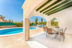 a patio with a table and chairs next to a swimming pool at Villa Luna by Villa Plus in Cala'n Bosch