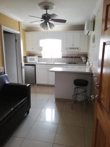 a kitchen with white cabinets and a ceiling fan at Suites Leon Rojo in Tijuana