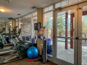 een fitnessruimte met cardio-apparatuur en een glazen deur bij Fenwick Vacation Rentals Inviting Rocky Mountain HOT TUB in Top Rated Condo in Canmore