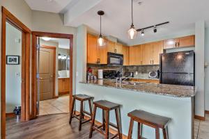 een keuken met houten kasten en een aanrecht met krukken bij Fenwick Vacation Rentals Inviting Rocky Mountain HOT TUB in Top Rated Condo in Canmore
