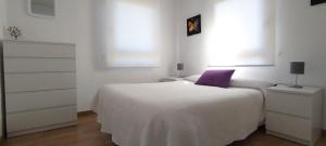 a white bedroom with a white bed with a purple pillow at Villa Lalia, ideal familias con niños in Camargo