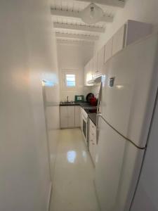 cocina blanca con nevera y fregadero en Fabrica Sunset Apartments en Megali Ammos