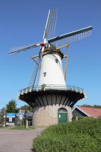 a mill with a windmill on top of it at B&B de Hartewens in Zuidland