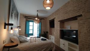 een slaapkamer met een bed, een televisie en een tafel bij Apartamentos Giralda, centro Histórico Sevilla in Sevilla
