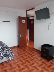 Habitación con cama y TV de pantalla plana. en HOSTAL EL CARIBE, en Ayacucho