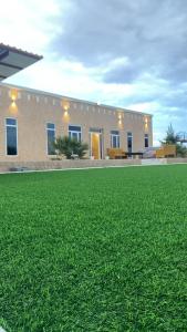 a building with a field of grass in front of it at مزرعه فلج المعلا in Falaj al Mu‘allá