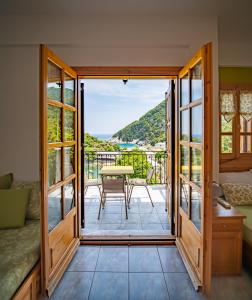 a room with a door open to a balcony with a table at Olive House in Damouchari with a sea view - Delicious Houses in Damouchari