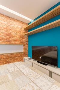 Habitación con TV de pantalla plana grande en una pared de ladrillo. en Otimo loft c WiFi a 500m da Praia de Copacabana RJ, en Río de Janeiro
