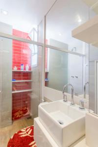 W białej łazience znajduje się umywalka i lustro. w obiekcie Otimo loft c WiFi a 500m da Praia de Copacabana RJ w mieście Rio de Janeiro