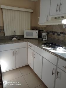 a kitchen with white cabinets and a microwave at Suites Leon Rojo in Tijuana