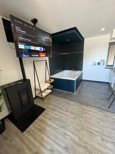 uma casa de banho com banheira e uma televisão num quarto em Privilège Spa, jacuzzi & Sauna 