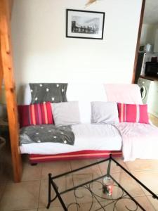 um sofá com almofadas vermelhas e brancas num quarto em Rez de jardin dans quartier calme et ensoleillé em Saint-André-les-Alpes