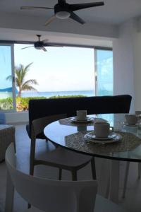 a dining room with a table and chairs with a view of the ocean at Beach Front Renewed Apartment in Cancún