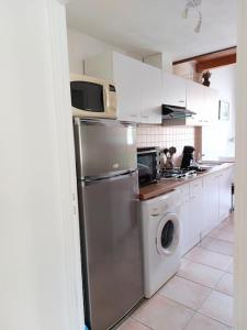 uma cozinha com um frigorífico de aço inoxidável e uma máquina de lavar louça em Rez de jardin dans quartier calme et ensoleillé em Saint-André-les-Alpes