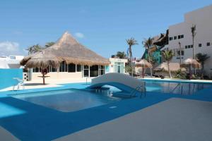 a large swimming pool with a thatch roof at Beach Front Renewed Apartment in Cancún
