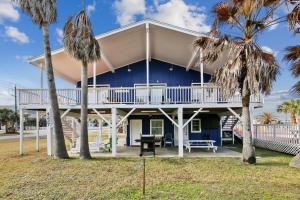 Casa azul con balcón y palmeras en The Happy Clam, en Galveston