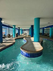 a swimming pool with blue columns in a building at Bayview Resort Penthouse w/ Sunset Views in Myrtle Beach