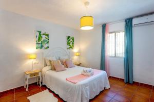 - une chambre avec un lit blanc et des oreillers roses dans l'établissement Villa Piedras Blancas by Villa Plus, à Frigiliana