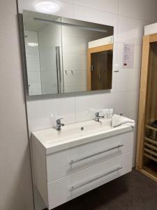 een badkamer met een witte wastafel en een spiegel bij Holiday Home Maridu Wellness in Arnhem