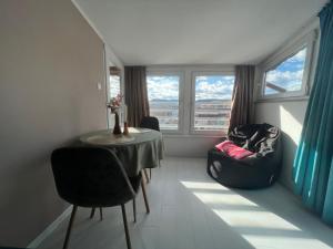 - un salon avec une table, des chaises et des fenêtres dans l'établissement Town Place Apartment, à Kardjali