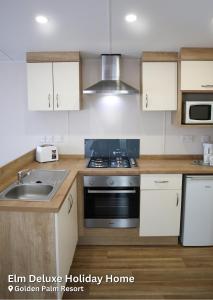 a kitchen with a sink and a stove top oven at Elm Deluxe Holiday Home in Chapel Saint Leonards