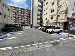 a parking lot with parked cars in a city at Rakuchin in Naha