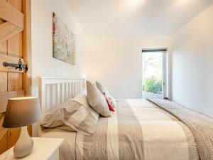um quarto com uma cama com um candeeiro e uma janela em Pightle Cottage em Poringland