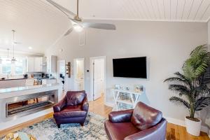 a living room with two chairs and a flat screen tv at Sea N Red - upper in Oak Island