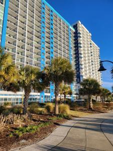 a large building with palm trees in front of a street at Bayview Resort Penthouse w/ Sunset Views in Myrtle Beach