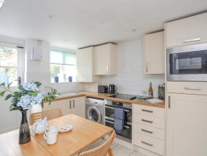 a kitchen with white cabinets and a wooden table at Blue Cottage in Beaumaris