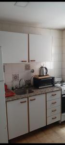 a kitchen with white cabinets and a sink and a stove at Hermoso departamento Tucuman in San Miguel de Tucumán