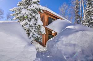 a log cabin covered in snow next to a tree at Peaceful Utah Ski-InandSki-Out Vacation Rental! in Beaver
