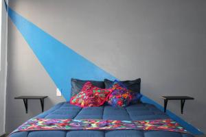 Una cama azul con dos almohadas coloridas. en Am Condesa en Ciudad de México